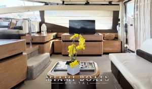 Luxury interior of the Azimut Yacht saloon. Spacious area for a boat party, with white leather sofas, a TV, and a coffee table.