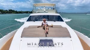 Girl getting a suntan on the bow of 70' Ferretti Luxury Yacht. View from the front.