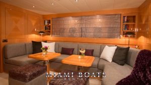 Dining area in the main salon of the 72' Mangusta Luxury Yacht. Couch and two wooden tables.