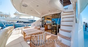 Aft deck of the 75' Sunseeker yacht with leather couch, chairs and wooden table on it.