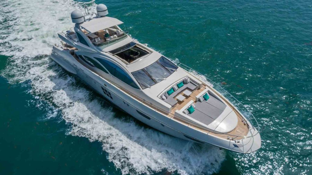 103’ Azimut Yacht sailing in Miami, with luxury deck featuring grey and teal cushions, white superstructure, and frothy wake, epitomizing performance and elegance.