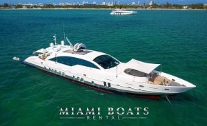 Luxury Yacht Tecnomar 120' in Miami, FL. in the bow of the boat is oval sofa and the opened big umbrella protection from sun. Super Yacht on the water in Miami
