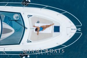 The bow of the 40 Beneateau yacht. Girl getting a suntan in bikini. Top view.