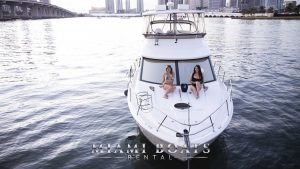 Two girls sitting on a bow deck of the boat in Miami. The 45 feet Meridian Yacht flybridge on the water in Miami