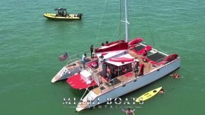 48' Catamaran boat in Miami. People onboard and swimming in the ocean. Paddle board next to the 48' Catamatan boat.