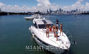 Yacht Rental Miami. Sunseeker Yacht Predator 60ft. The Sport Boat on the water in Miami, and people are having fun in the front of the boat in good weather.