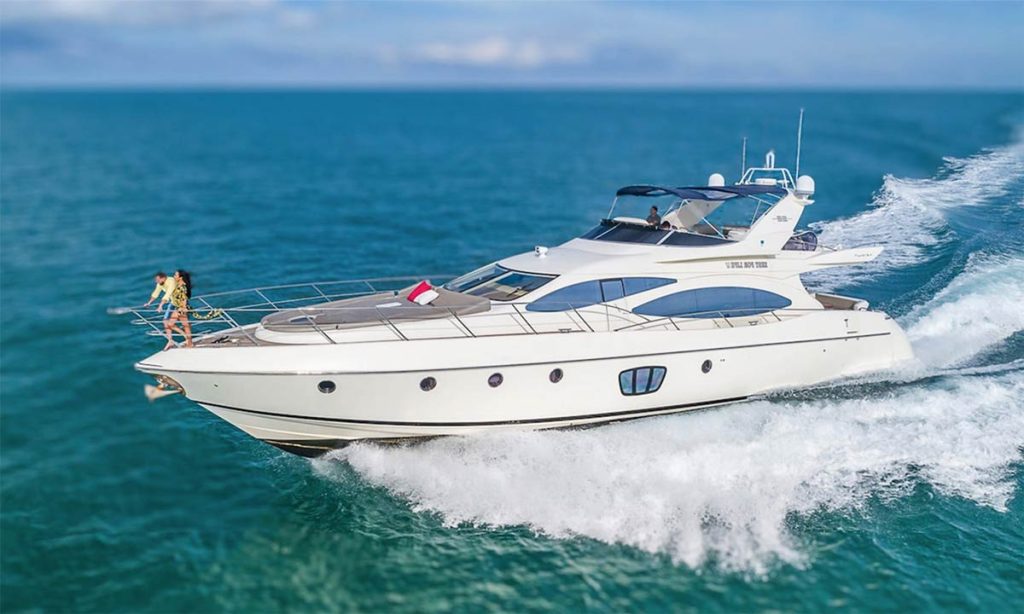 The 68' Azimut Yacht Flybridge glides over the Miami waters, its white exterior gleaming in the sunlight. At the bow, a couple enjoys the thrill of the ride, creating a feeling of connection and freedom at sea.