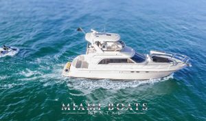 The 55’ Sea Ray Sedan ‘Island Itch’ is captured in motion with a jet ski riding nearby, emphasizing its sporty elegance, spacious flybridge, and open aft deck — perfect for active charters and luxury escapes.