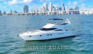 Luxury yacht rental in Miami – a stunning 60’ Viking Princess yacht cruising on turquoise waters with the iconic Miami Downtown skyline in the background. This sleek white yacht features a spacious flybridge with a shaded seating area, perfect for private charters, special events, and luxury boat experiences. “Miami Boats Rental” branding is displayed at the bottom.